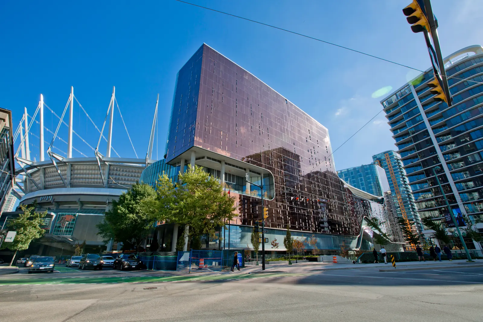 Parq Vancouver's copper-glass tower beside the masts of BC Place on a sunny day